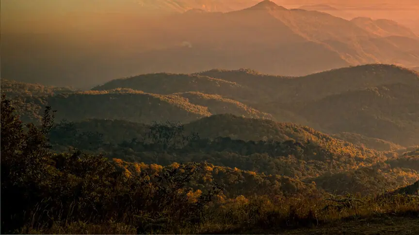 Forested ridge and valley layers below the sunset sky